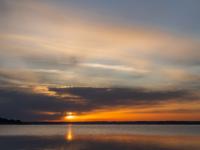 Die Morgensonne schiebt sich hinter die dunkle Wolkenschicht